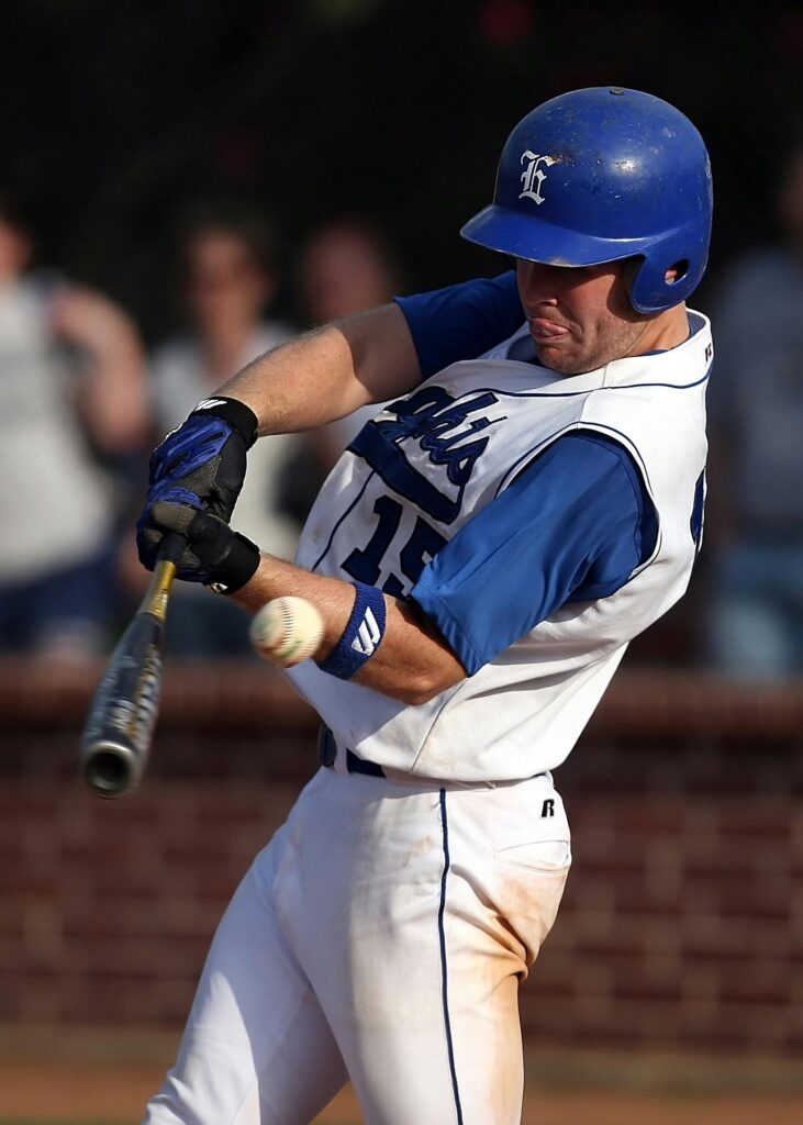 Dynamic shot of a baseball player swinging a bat during a game, wearing a blue and white uniform.