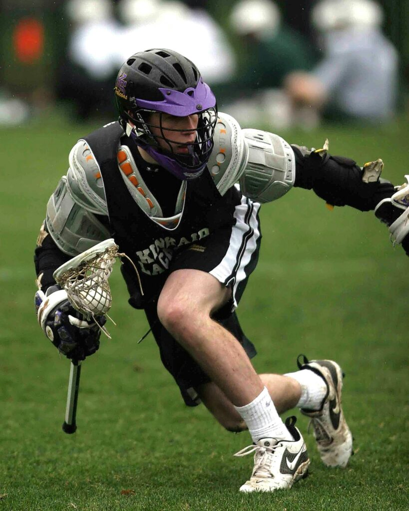 Dynamic shot of a lacrosse player mid-action during a sports game.