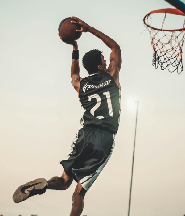 A dynamic basketball player executing a slam dunk during a vibrant outdoor game.