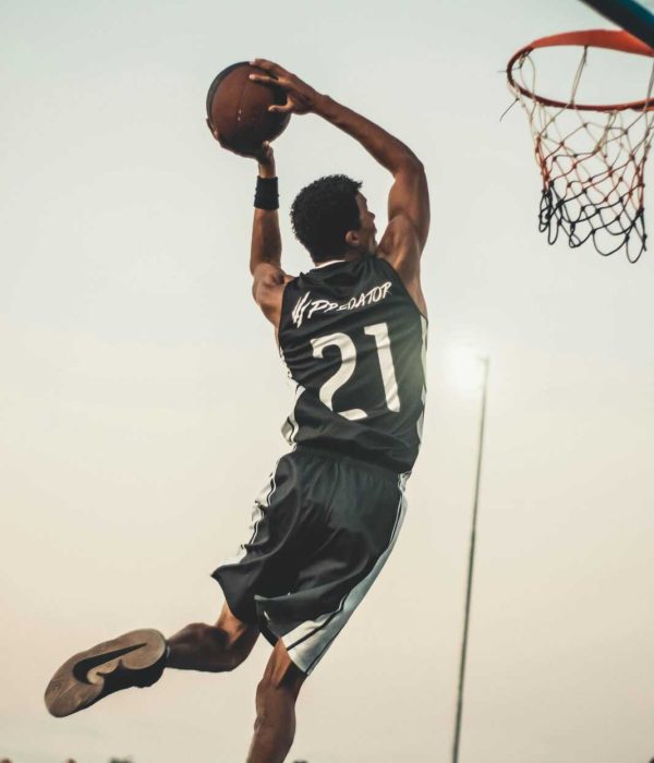 A dynamic basketball player executing a slam dunk during a vibrant outdoor game.