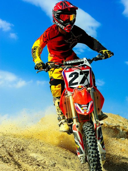 Motocross rider speeding on dirt track, showcasing skill and adrenaline.
